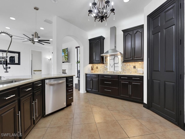 kitchen with light tile patterned floors, ceiling fan with notable chandelier, a sink, wall chimney range hood, and dishwasher