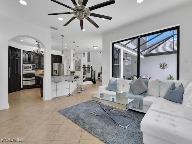 living room with arched walkways, light tile patterned floors, recessed lighting, visible vents, and ceiling fan with notable chandelier