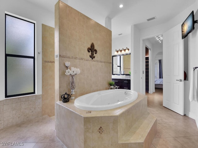 full bathroom with ensuite bathroom, a jetted tub, tile patterned flooring, vanity, and tile walls