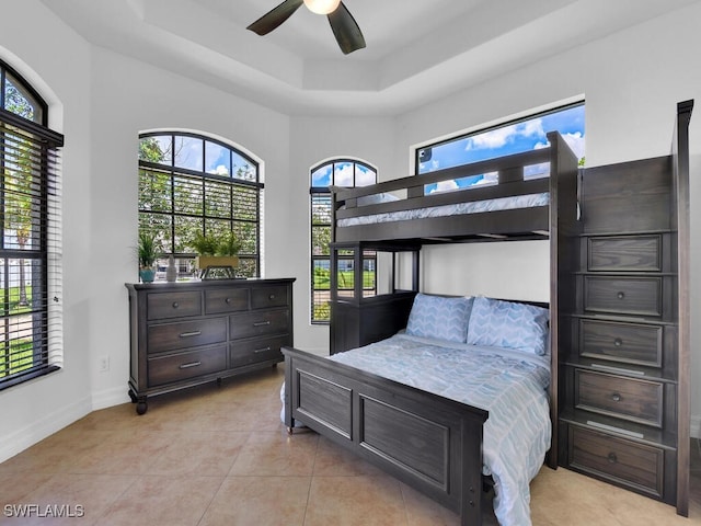 bedroom with light tile patterned flooring, a raised ceiling, and baseboards