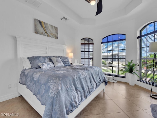 bedroom with baseboards, a raised ceiling, visible vents, and tile patterned floors