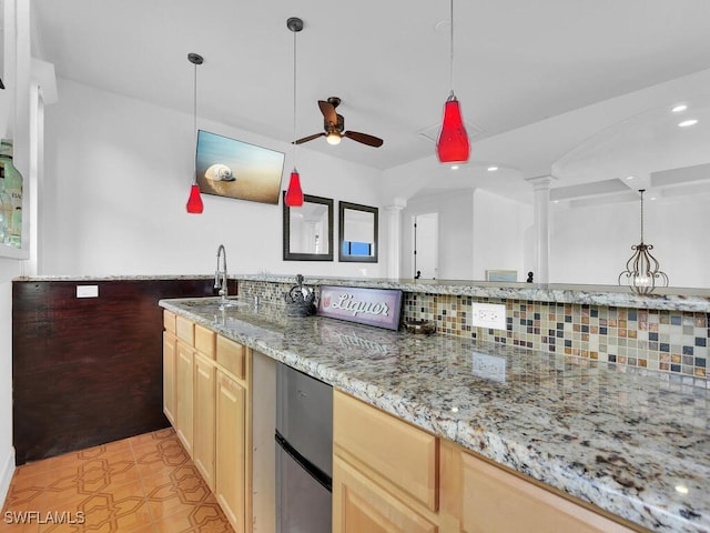 kitchen featuring decorative backsplash, light stone counters, ornate columns, light brown cabinets, and a sink