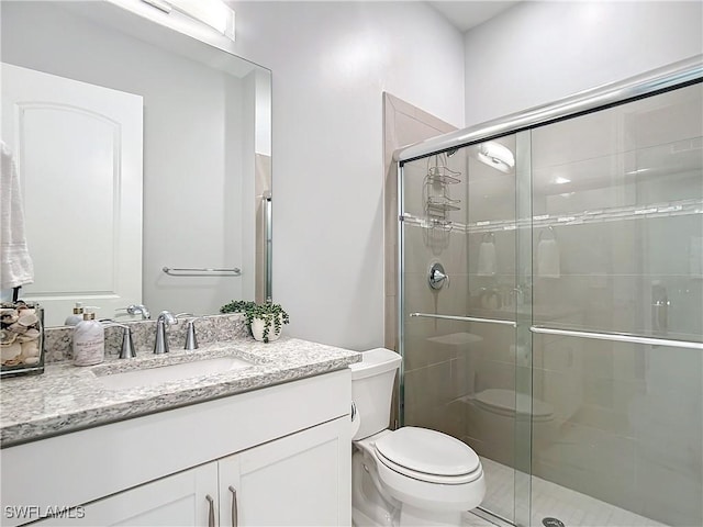 bathroom featuring a shower with shower door, toilet, and vanity