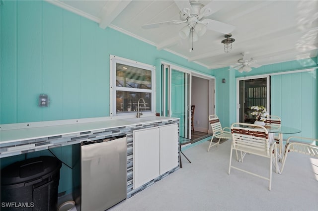 kitchen with refrigerator, ornamental molding, ceiling fan, sink, and beamed ceiling