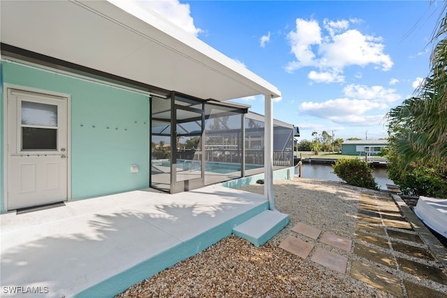 view of patio featuring a lanai and a water view