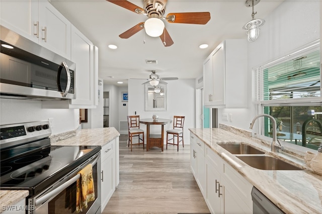 kitchen with light stone countertops, sink, white cabinets, and appliances with stainless steel finishes