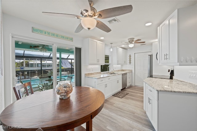 kitchen with sink, light stone counters, stainless steel dishwasher, white cabinets, and light wood-type flooring