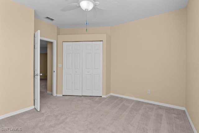 unfurnished bedroom featuring ceiling fan, light colored carpet, and a closet