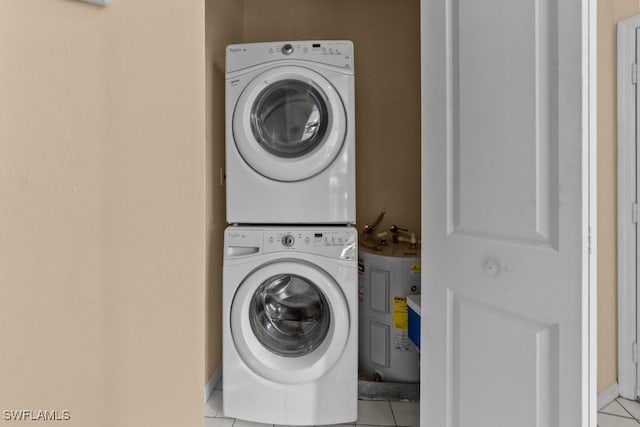 clothes washing area featuring light tile patterned flooring and stacked washer and clothes dryer