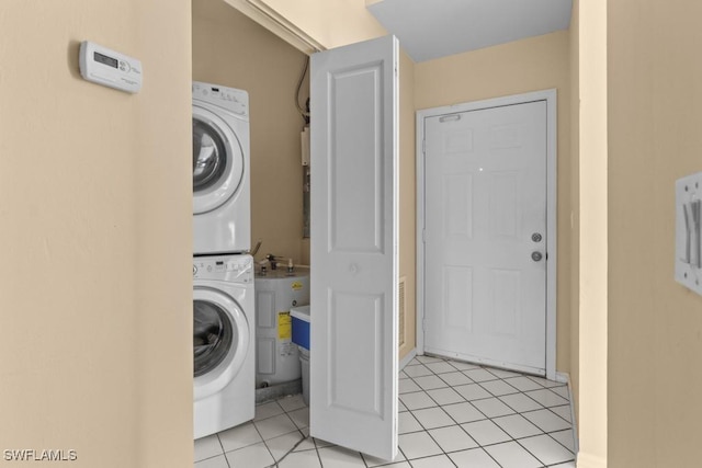 laundry area with stacked washer / drying machine and light tile patterned flooring