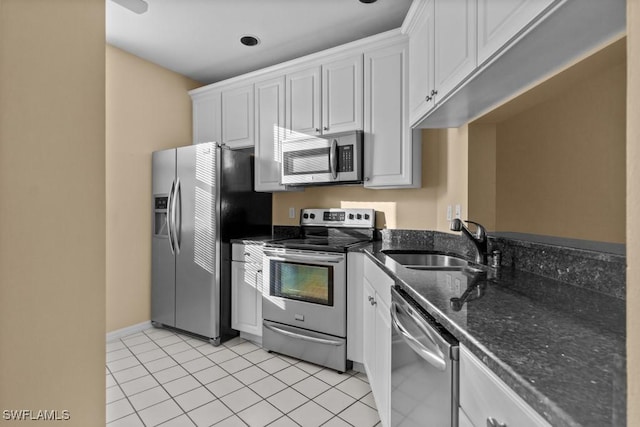 kitchen featuring white cabinetry, sink, dark stone countertops, light tile patterned floors, and appliances with stainless steel finishes