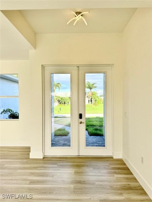 doorway featuring light hardwood / wood-style floors, an inviting chandelier, and french doors