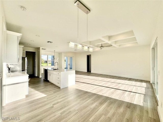 kitchen featuring pendant lighting, sink, white cabinetry, and an island with sink