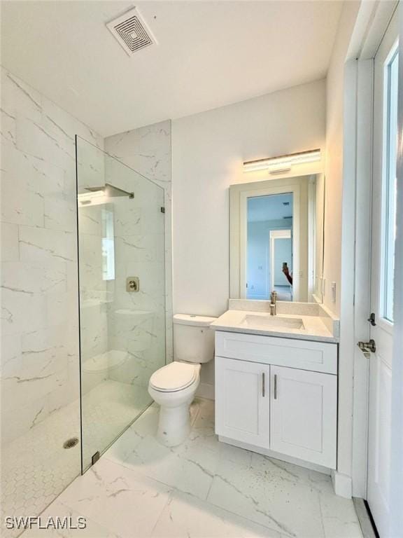 bathroom featuring tiled shower, vanity, and toilet