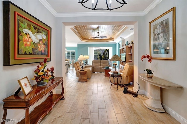 hallway featuring crown molding, a tray ceiling, light hardwood / wood-style flooring, and a chandelier