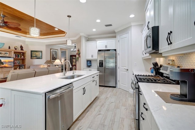 kitchen with pendant lighting, stainless steel appliances, an island with sink, and white cabinets