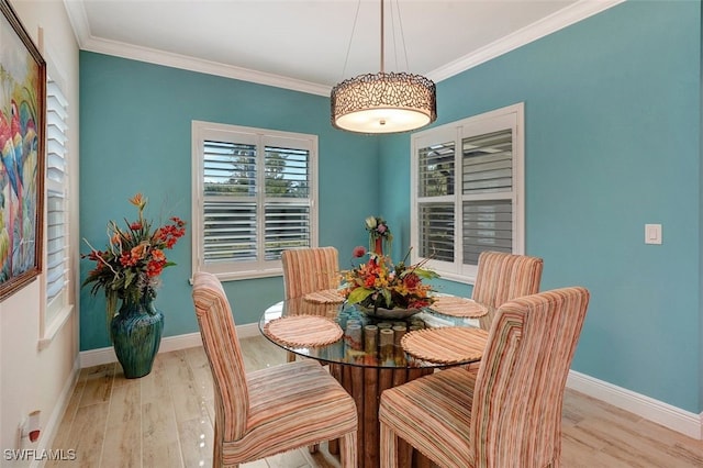 dining space with ornamental molding and light hardwood / wood-style floors