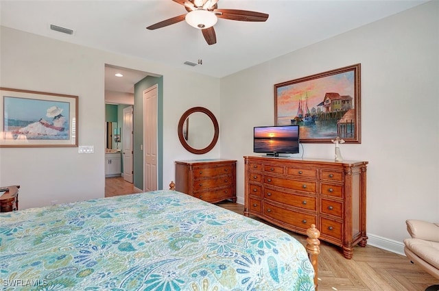 bedroom featuring ceiling fan, ensuite bath, and light parquet flooring