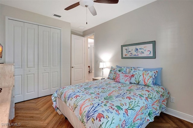 bedroom with parquet floors, ceiling fan, and a closet