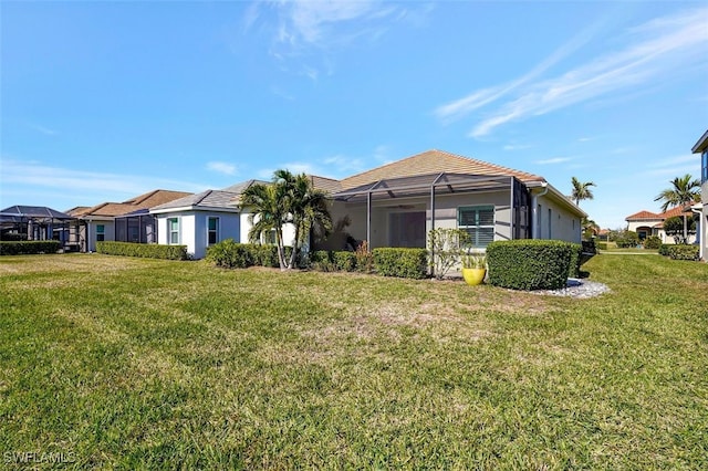 rear view of property with a lanai and a lawn