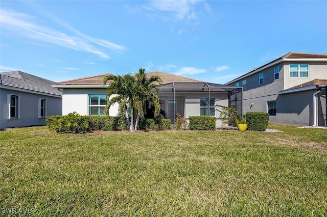 back of property with a yard and glass enclosure