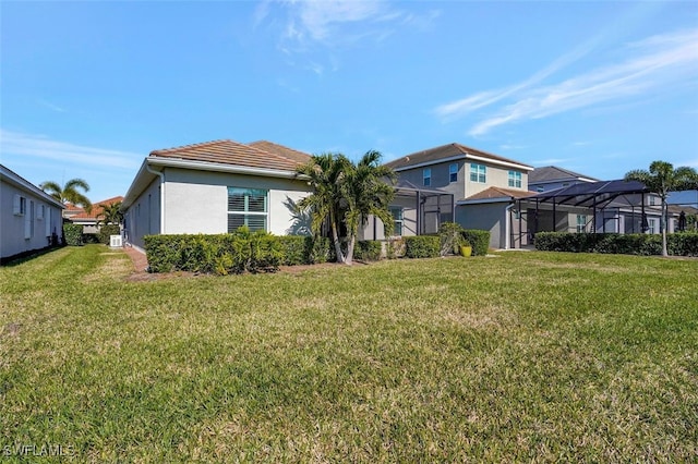 back of property with glass enclosure and a lawn