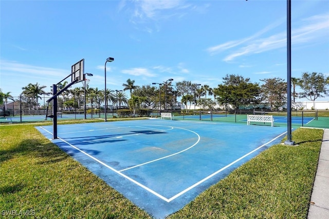 view of sport court featuring tennis court and a lawn