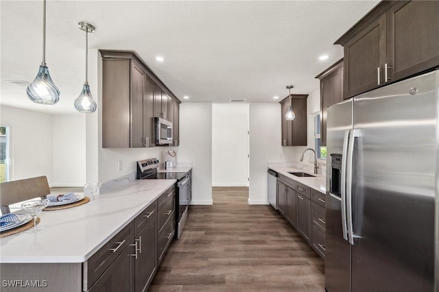 kitchen with light stone counters, dark brown cabinets, stainless steel appliances, sink, and decorative light fixtures