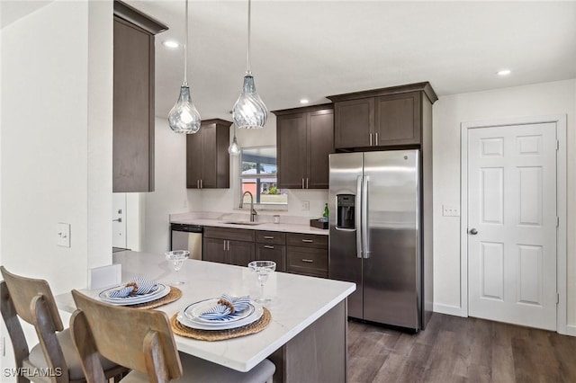 kitchen featuring pendant lighting, a breakfast bar, dark wood-type flooring, sink, and appliances with stainless steel finishes