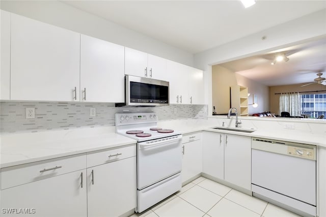 kitchen with white appliances, backsplash, white cabinetry, and sink