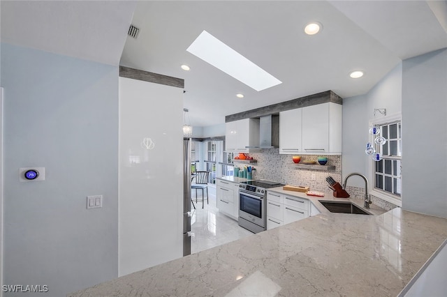 kitchen with stainless steel electric range, wall chimney range hood, sink, a skylight, and white cabinetry