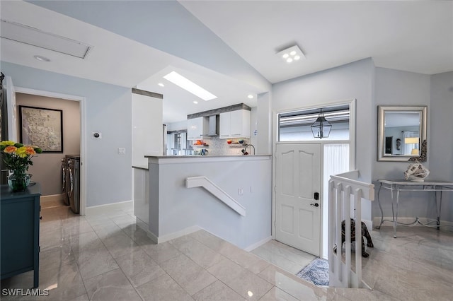 entryway featuring lofted ceiling with skylight and washing machine and clothes dryer