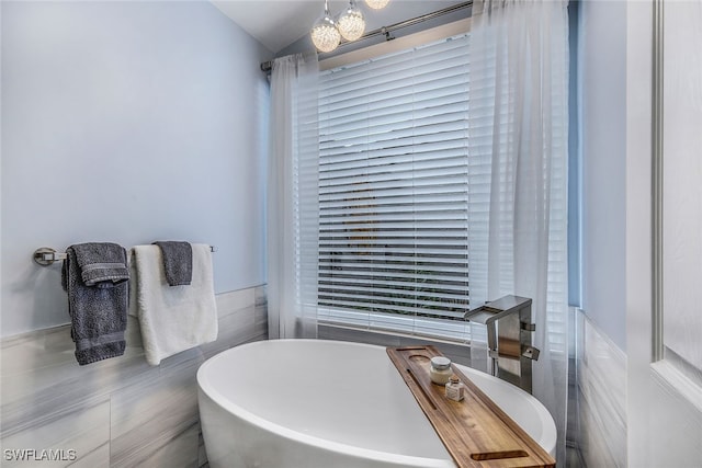 bathroom featuring vaulted ceiling, tile walls, and a bathing tub