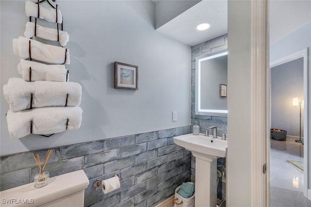 bathroom featuring tile walls and toilet