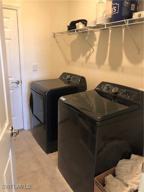 clothes washing area with washing machine and dryer and light tile patterned floors