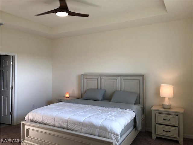 carpeted bedroom with ceiling fan and a raised ceiling