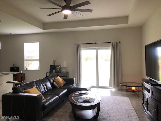 living room with a wealth of natural light, a raised ceiling, and light tile patterned floors