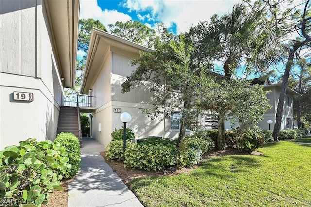 view of property exterior with stairs and a lawn