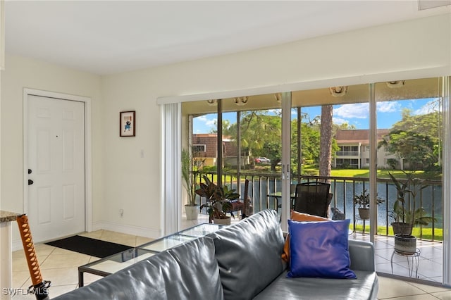 living room featuring a water view, baseboards, and light tile patterned floors