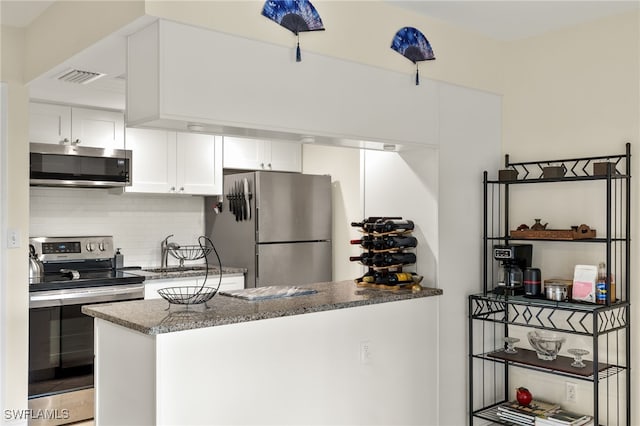 kitchen with stainless steel appliances, visible vents, decorative backsplash, white cabinetry, and a peninsula