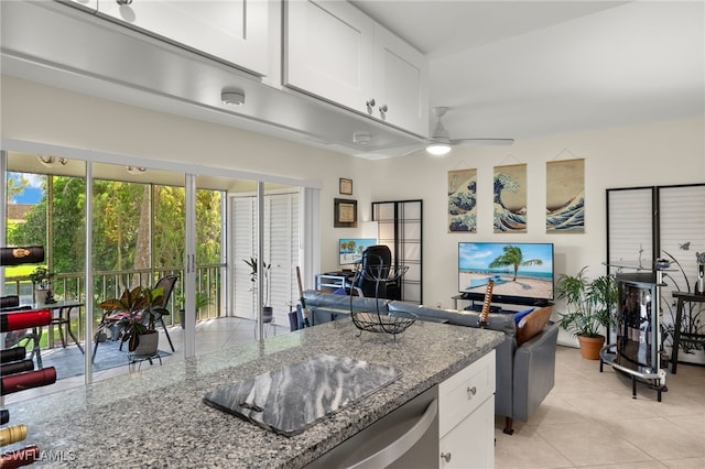 kitchen featuring light tile patterned floors, ceiling fan, open floor plan, stone counters, and white cabinetry