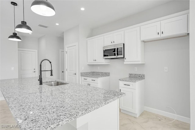 kitchen with a center island with sink, white cabinets, and sink