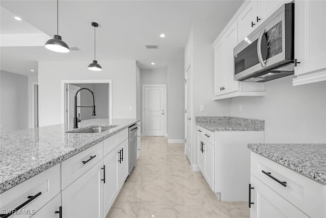 kitchen featuring pendant lighting, white cabinets, sink, light stone counters, and stainless steel appliances