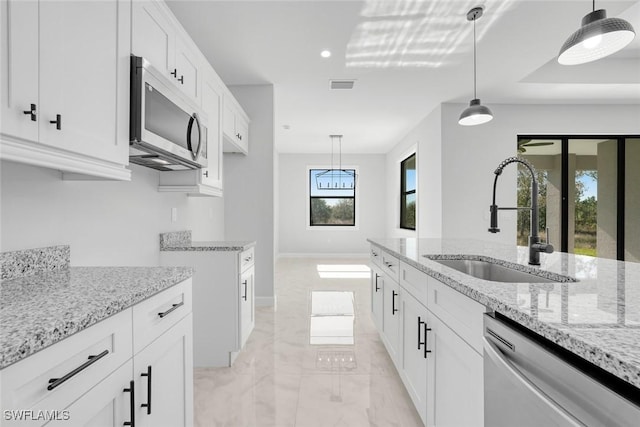 kitchen featuring light stone counters, stainless steel appliances, sink, pendant lighting, and white cabinets