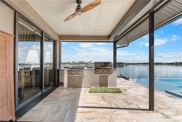 view of patio featuring ceiling fan, area for grilling, exterior kitchen, and a water view