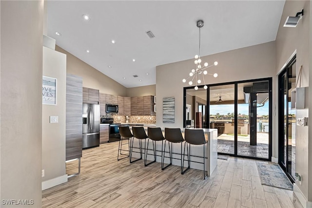 kitchen featuring a kitchen breakfast bar, pendant lighting, stainless steel fridge with ice dispenser, black range with electric cooktop, and decorative backsplash