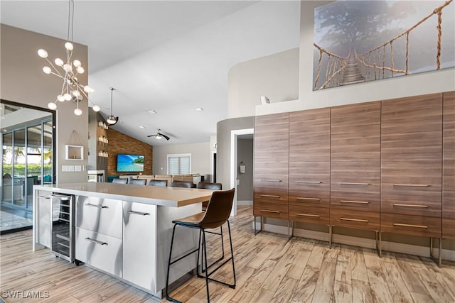 kitchen with pendant lighting, white cabinetry, a notable chandelier, a kitchen island, and beverage cooler