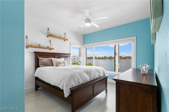 bedroom with ceiling fan, light hardwood / wood-style flooring, and a water view