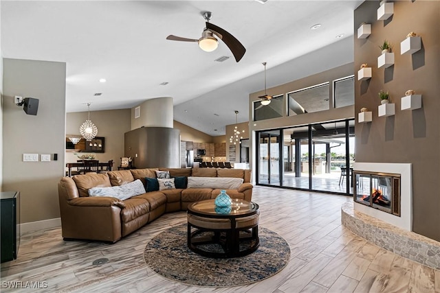 living room featuring a multi sided fireplace, ceiling fan with notable chandelier, and lofted ceiling