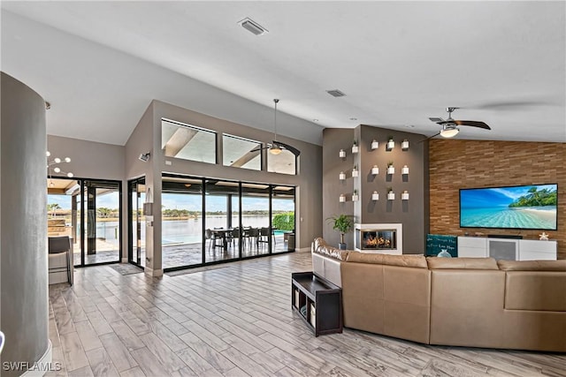 living room featuring ceiling fan, high vaulted ceiling, and a fireplace